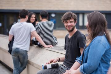 Students outside sitting on wall and chatting